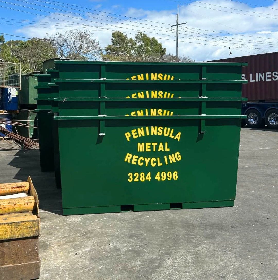 Stacked green Peninsula Metal Recycling bins with the business name and phone number painted on the side